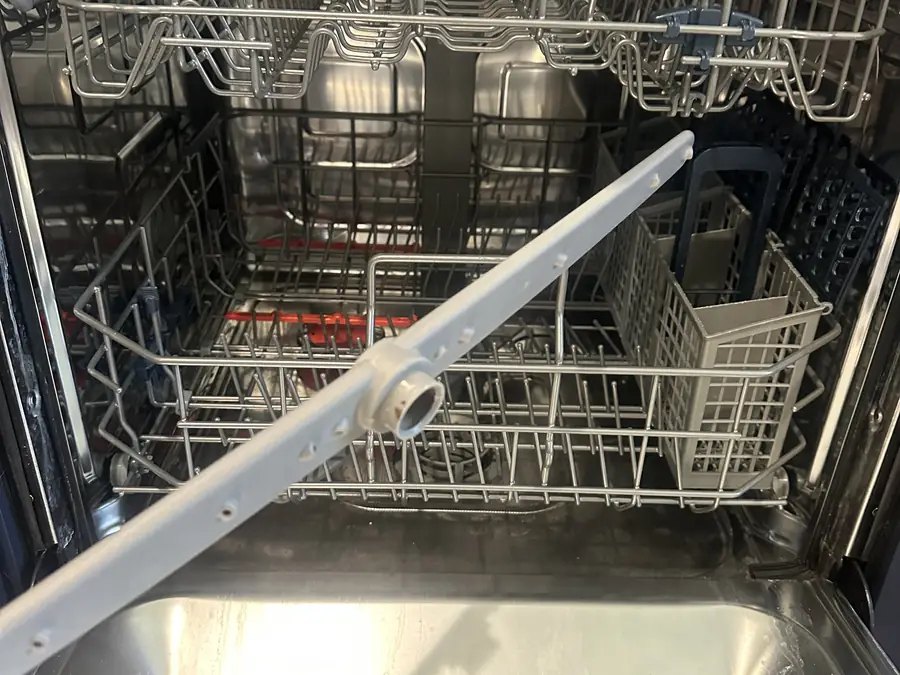 Dishwasher with the racks out and the spray arm exposed during a repair